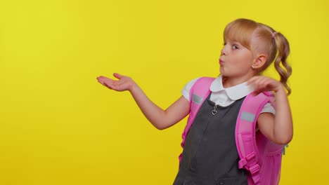 school girl kid in uniform showing thumbs up, pointing left at copy space for promotional content