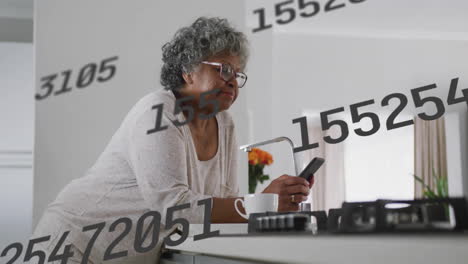 elderly woman using smartphone in kitchen with floating numbers animation overlay