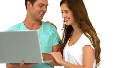 una pareja sonriente usando una computadora portátil
