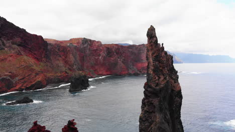 Drone-turning-around-cliff-in-water-Sao-Lourenco-Madeira,-Portugal