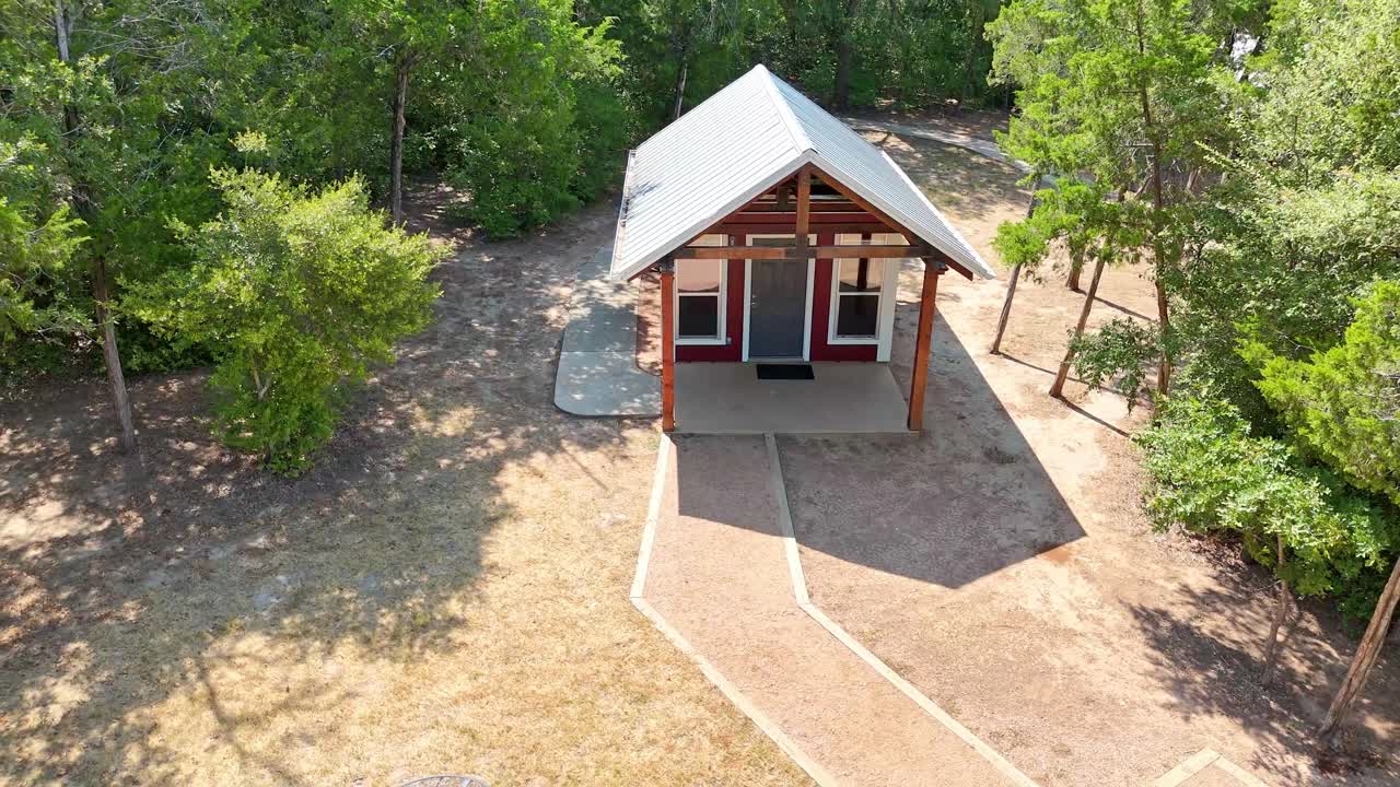 alejándose de un pequeño campamento de cabaña aislado que está rodeado de muchos árboles