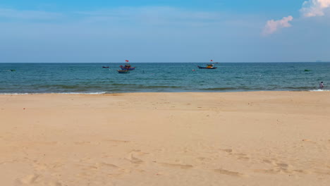 Two-Vietnamese-Fishing-Boats-Anchored-Floating-Off-Shore-In-Clean-Empty-Beach-During-Clear-Daytime