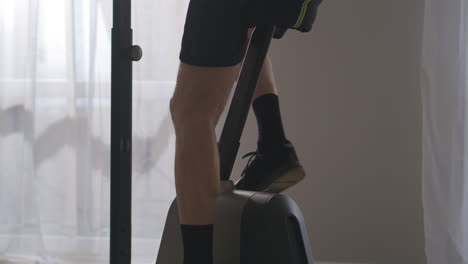 legs of slender aged man training on stationary bicycle in room closeup view losing weight and keeping good physical condition in middle age