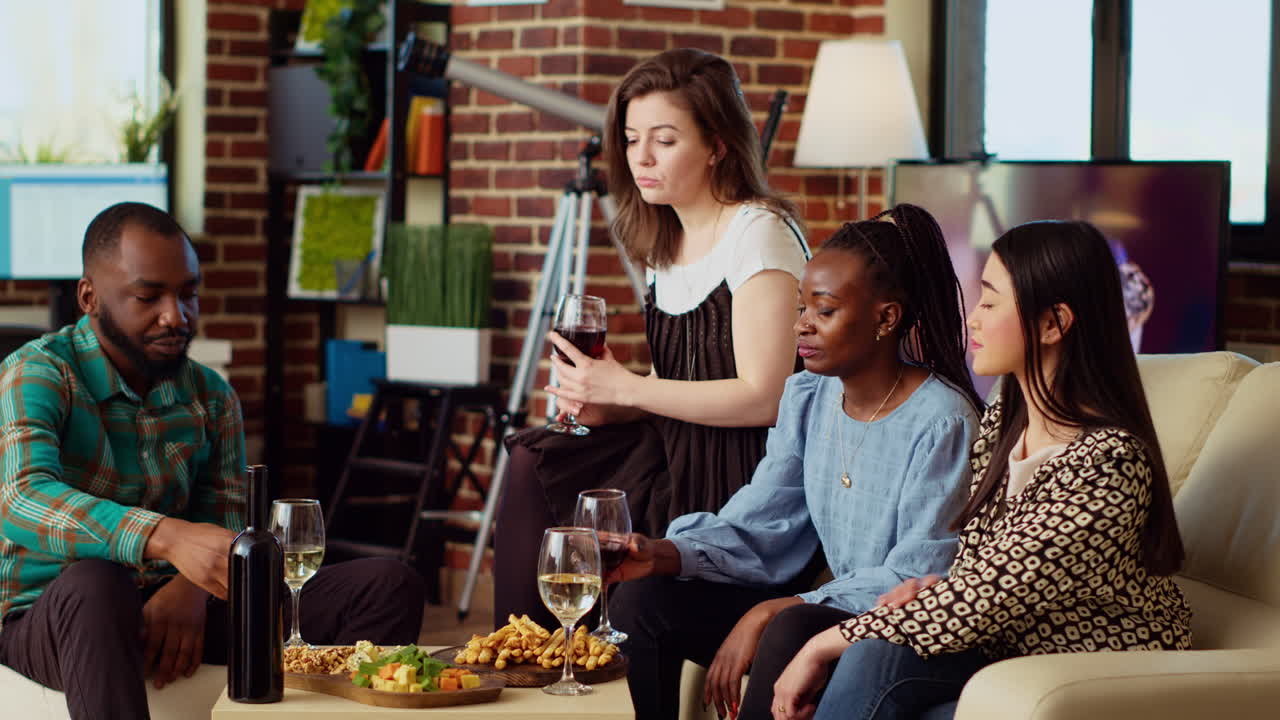 Friends laughing, toasting with alcoholic drinks, celebrating special occasion in apartment