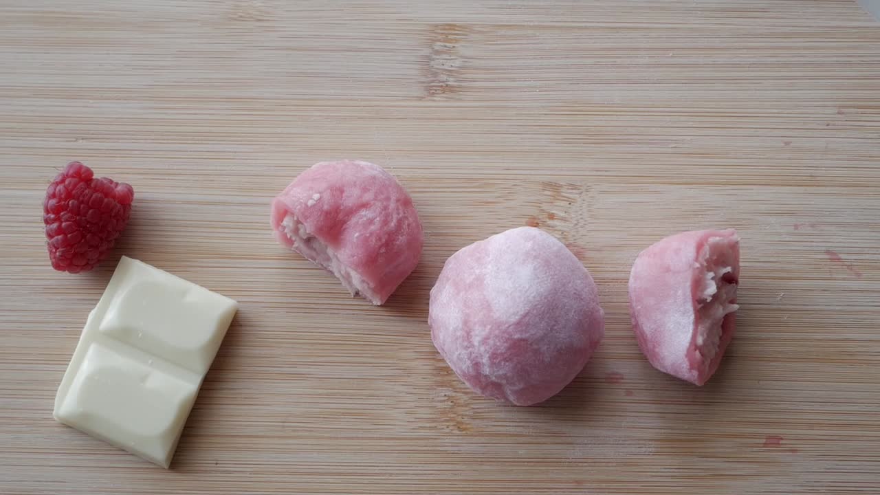Soft pink mochi filled with strawberry and white chocolate, cut in half to show filling