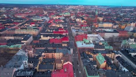 drone shot of stockholm, sweden, flying above downtown buildings and streets at sunset