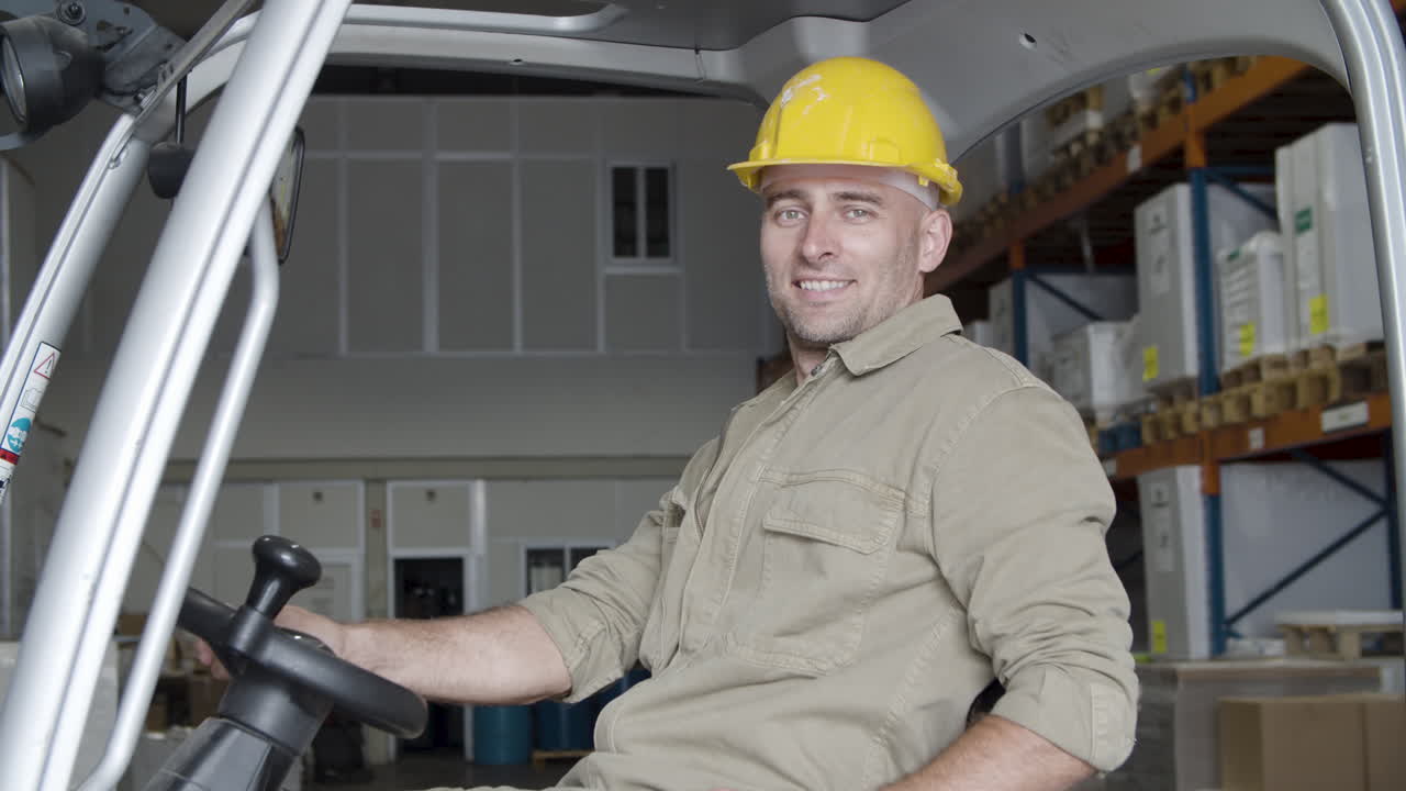 Happy Caucasian male worker sitting in forkfit and looking at the camera