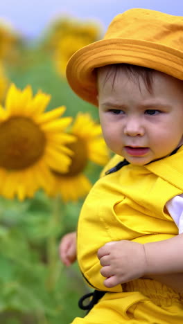 baby in a yellow outfit in a sunflower field