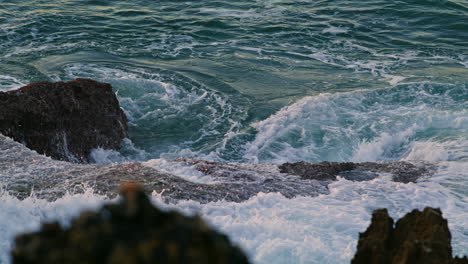 Aufgewühltes-Meer,-Das-Felsen-In-Der-Abenddämmerung-Umspült,-Nahaufnahme.-Wirbelndes-Wasser-Trifft-Auf-Ufer