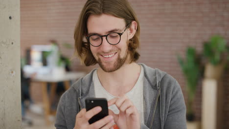 Retrato-De-Un-Joven-Usando-Un-Teléfono-Inteligente-Enviando-Mensajes-De-Texto-A-Un-Estudiante-Guapo-Navegando-Mensajes-En-Línea-Enviando-Sms-En-Un-Teléfono-Móvil-Sonriendo-Feliz-Usando-Gafas