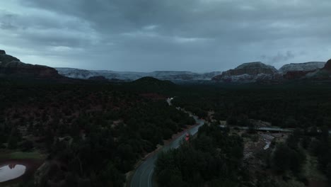 carretera con vehículos que viajan en sedona, arizona en una puesta de sol nublada - toma aérea de drones