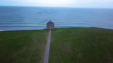 Aerial-shot-of-Mussenden-Temple-located-on-cliffs-near-Castlerock-in-County-Londonderry,-high-above-the-Atlantic-Ocean-on-the-north-western-coast-of-Northern-Ireland