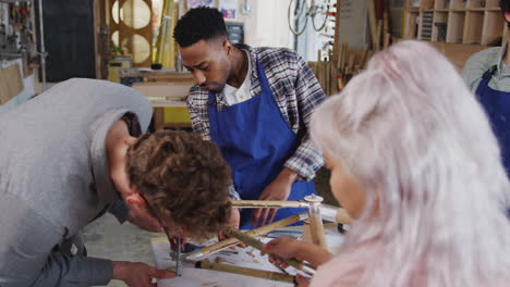 multi-cultural team of trainees in workshop learn how to assemble hand built bamboo bicycle frame