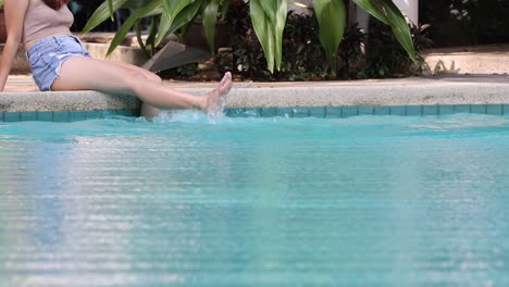 person splashing water with feet at poolside.