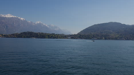 boat cruising on lake como with mountains in background in bellagio, italy