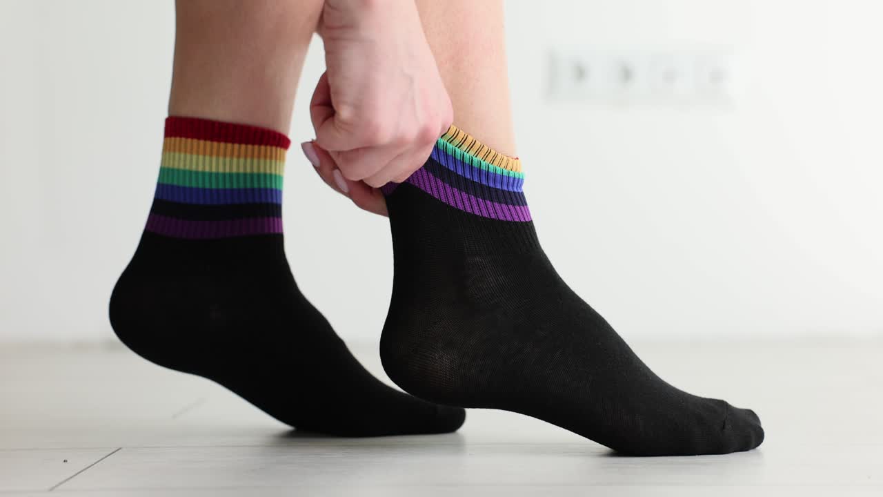 Persona indossa calzini neri a strisce multicolori arcobaleno