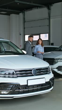 car salesman discussing vehicle with customer in showroom