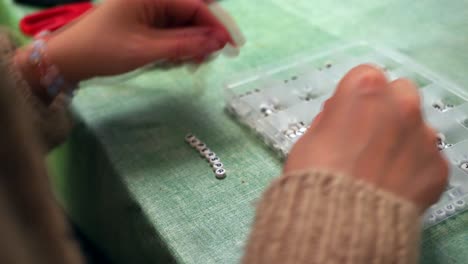 Primer-Plano-De-La-Fabricación-De-Joyas-De-Pulsera,-Artesanía-Con-Cuentas-De-Alfabeto-Blanco