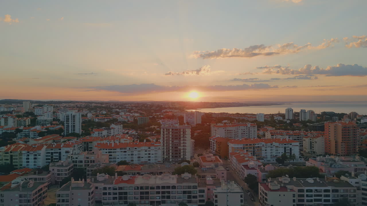Golden sundown coastal city drone view. Bright evening sunrise shining on town