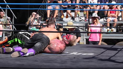 wrestlers compete in an outdoor wrestling ring.