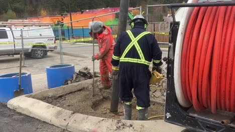 construction worker assists expert crew in safely exposing underground utility lines with hydrovac truck