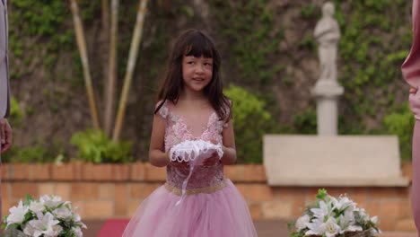 a young girl presents wedding rings on a pillow during a ceremony