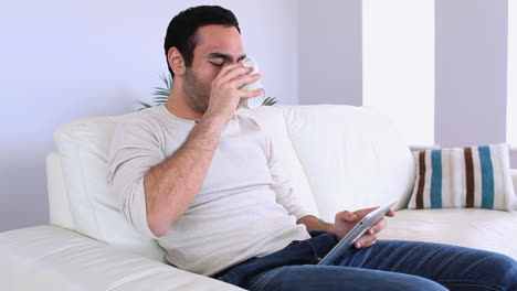 Un-Hombre-Guapo-Usando-Su-Tablet-Pc-Relajándose-En-Su-Sofá