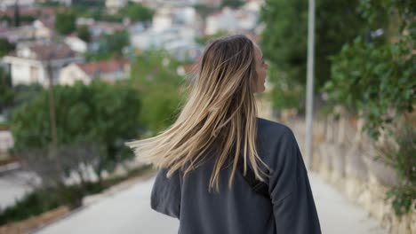 rear view of blonde young female traveler sightseeing and enjoying summer vacation in an old traditional costal town