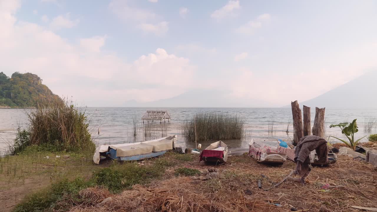 живописный вид небольших лодок на берегу озера атилан и трех гигантов, покрытых облаками на заднем плане