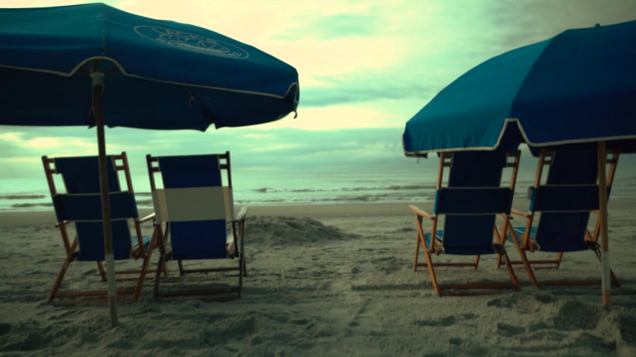 Lettini e ombrelloni da spiaggia sulla spiaggia di fronte all'oceano