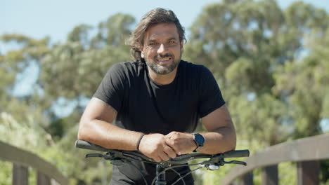 Retrato-De-Un-Atleta-Sonriente-De-Pie-Con-Una-Bicicleta-Al-Aire-Libre