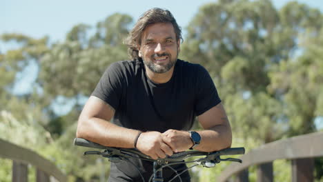 retrato de un atleta sonriente de pie con una bicicleta al aire libre