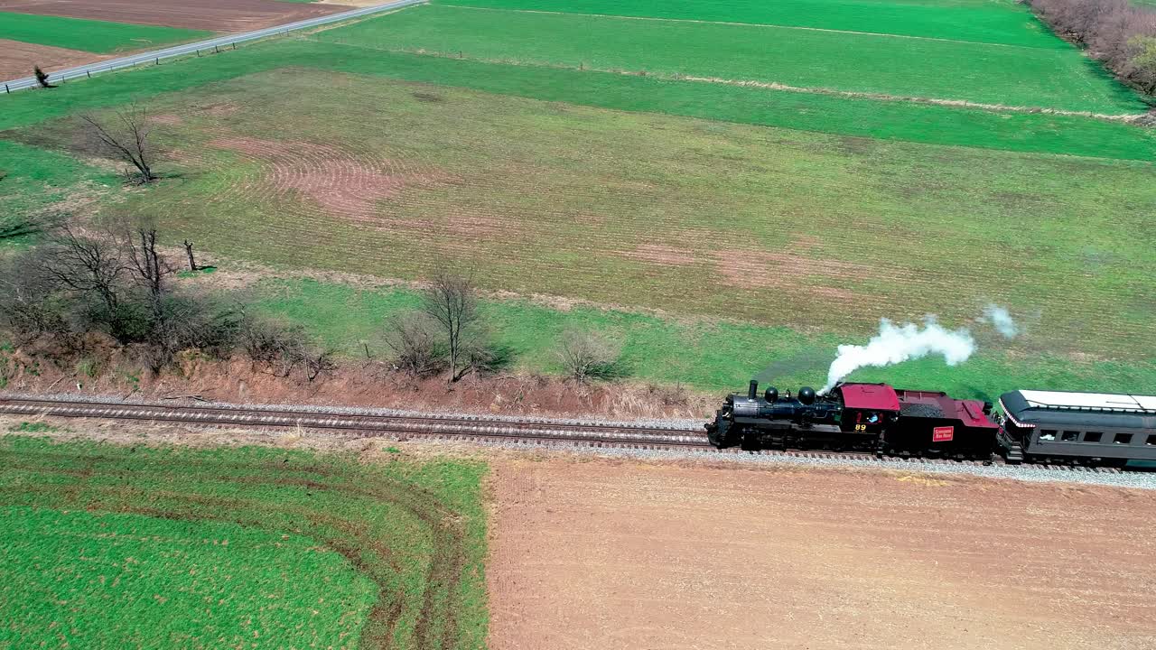 Aerial View of a Vintage Steam Train Traveling Through Lush Green Fields