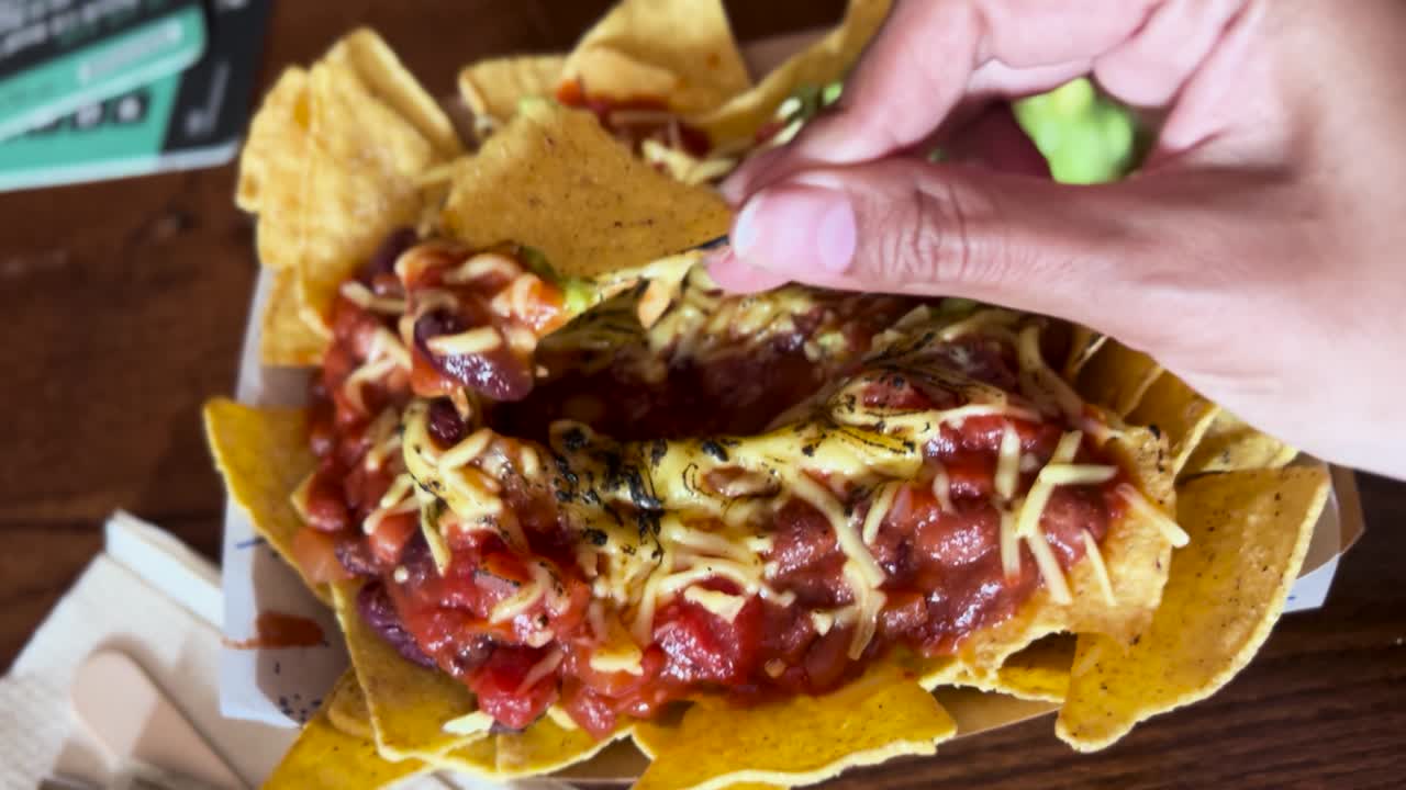 Scooping Loaded Nachos Cheese Topping with Tortilla Chip