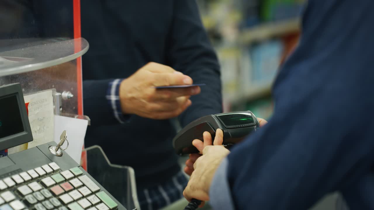 Authentic close up shot of smiling customer is giving a credit card to cashier for paying grocery food products in supermarket.