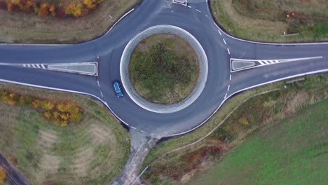 Lovely-Car-on-Roundabout,-Top-Down-Spinning-Cinematic-Aerial-View-of-Countryside-Road-and-Vehicle