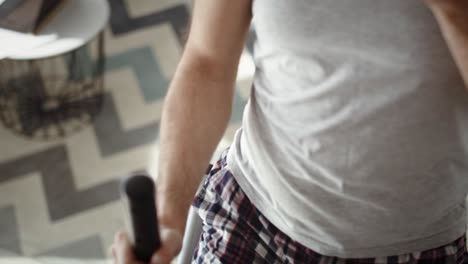 tilt up of man exercising on cross trainer at home