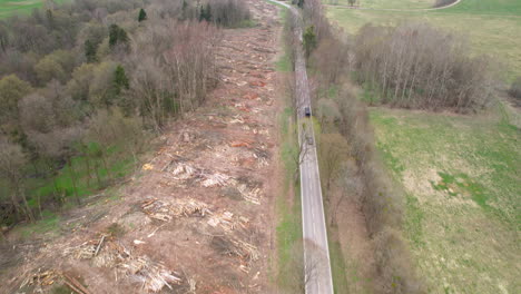 Aerial-birds-eye-shot-of-vehicle-on-road-in-woodland-after-deforestation-of-forest-in-Poland