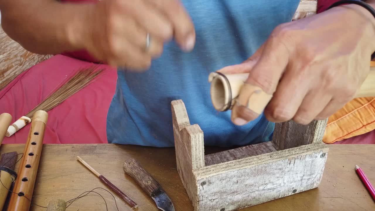 manos del fabricante tradicional de flauta de bambú, instrumento musical artesanía artesanal, técnica con madera, primer plano, indonesia, sudeste asiático