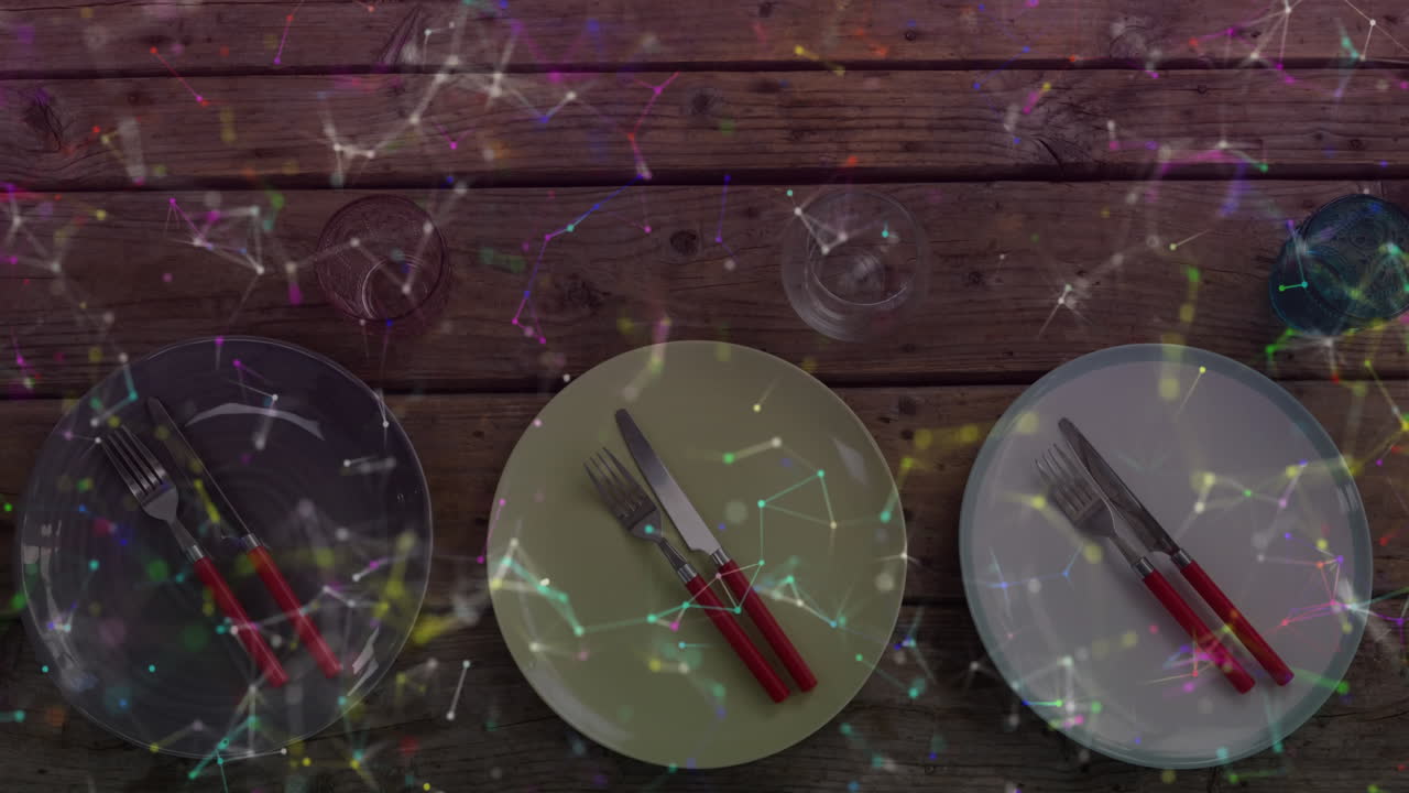 Displaying three plates, red-handled cutlery and glasses sliding on tabletop under network overlay