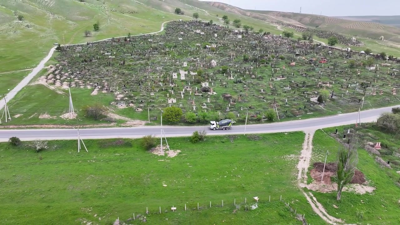 Caminhão passando na estrada perto de um cemitério histórico quirguiz, cena de transporte aérea. Bishkek
