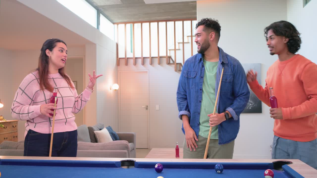 Diverse friends taking shots on blue felt table high fiving third friend joining planning next turn