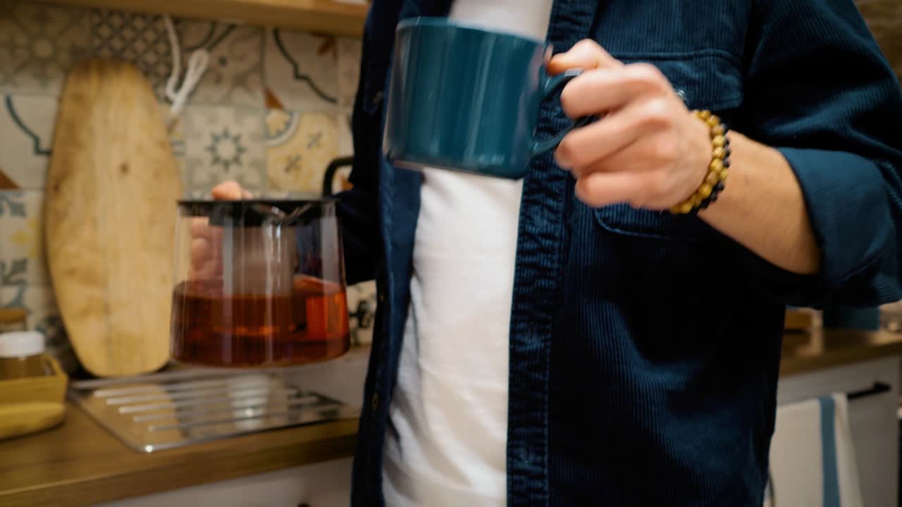 한 남자의 손은 컵에 차를 부어 그것을 마시고. 활기찬 차. 아름다운 아침