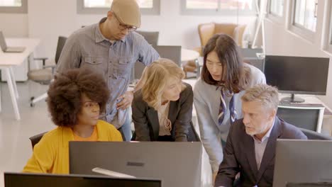 Business partners looking at the same computer in a coworking