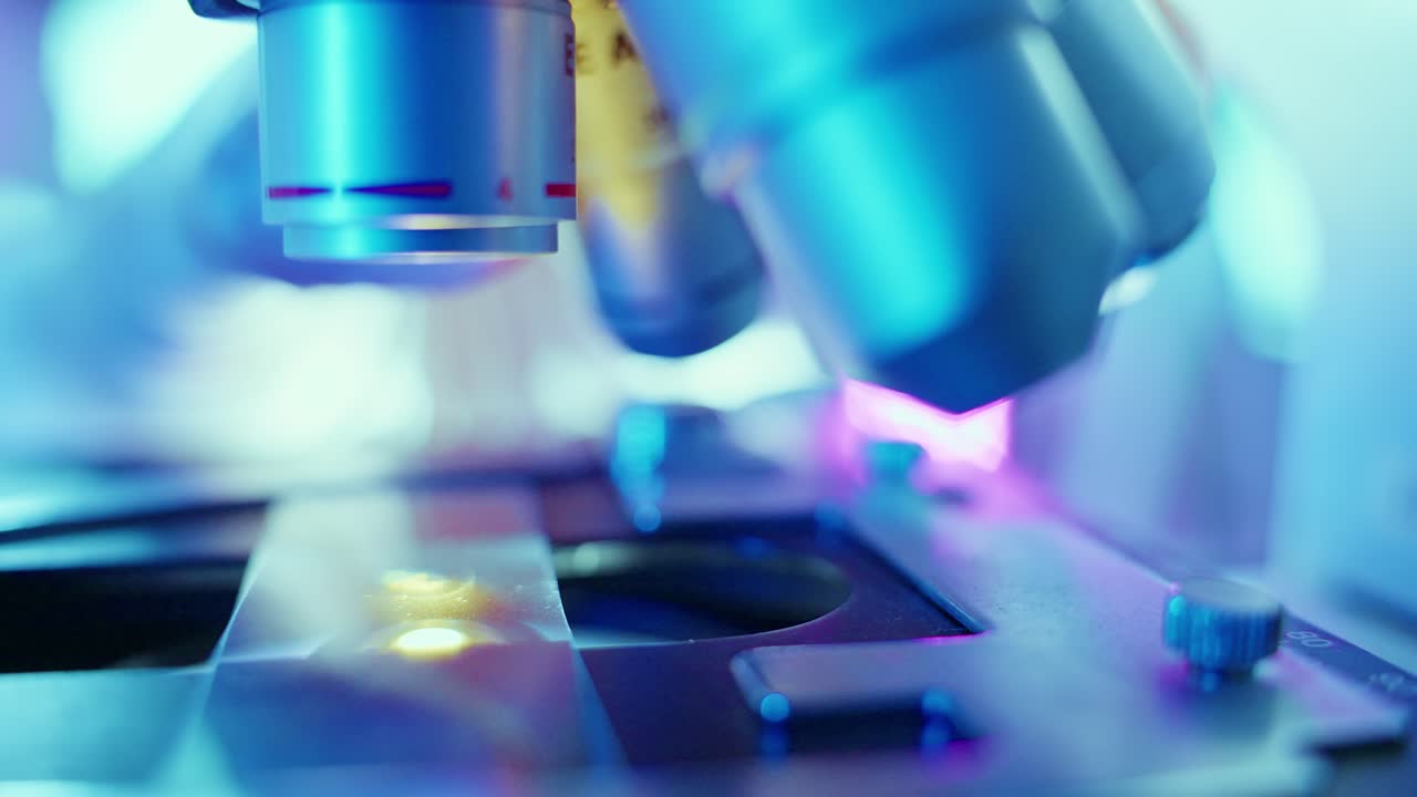 Close-up of Scientist Adjusting Microscope Lens in Laboratory