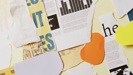 Video-of-close-up-of-collage-of-scraps-of-paper-and-newspaper-on-yellow-background