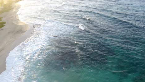 aerial pullback of deep blue water and coral reef revealing stunning golden sunrise light