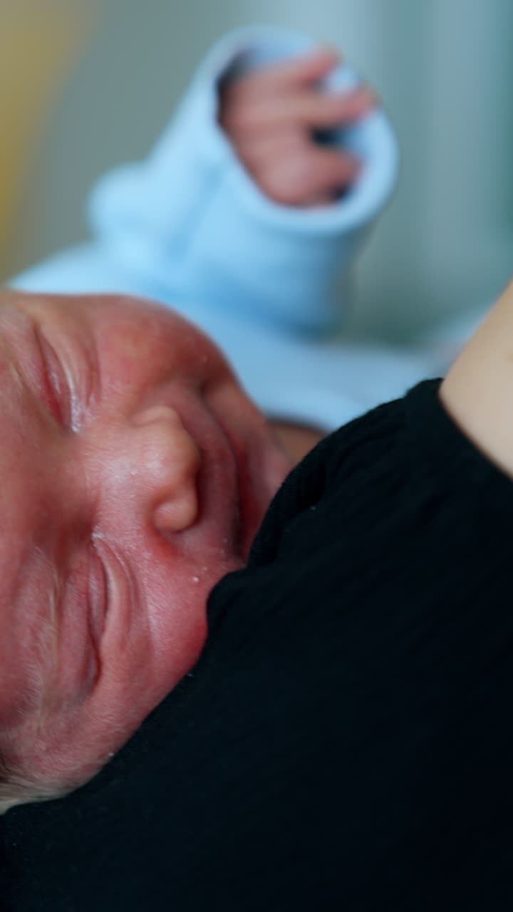 Little baby lying in mom's hands. Newborn falling asleep in mother's arms. Close up. Vertical video
