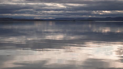 Heavy-clouds-backlit-by-the-sun-hang-above-the-calm-waters