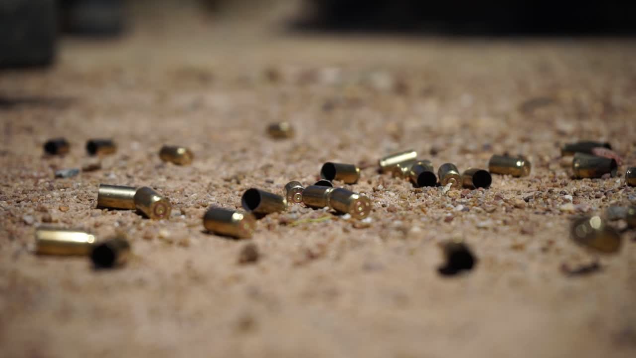 A close-up shot of bullet shells falling on the sandy ground